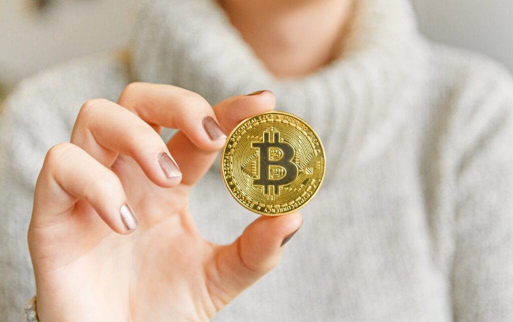 106820278 1609972654383 hand holding a bitcoin in front of a computer screen with a dark graph blockchain mining bitcoin t20 pRrrjP